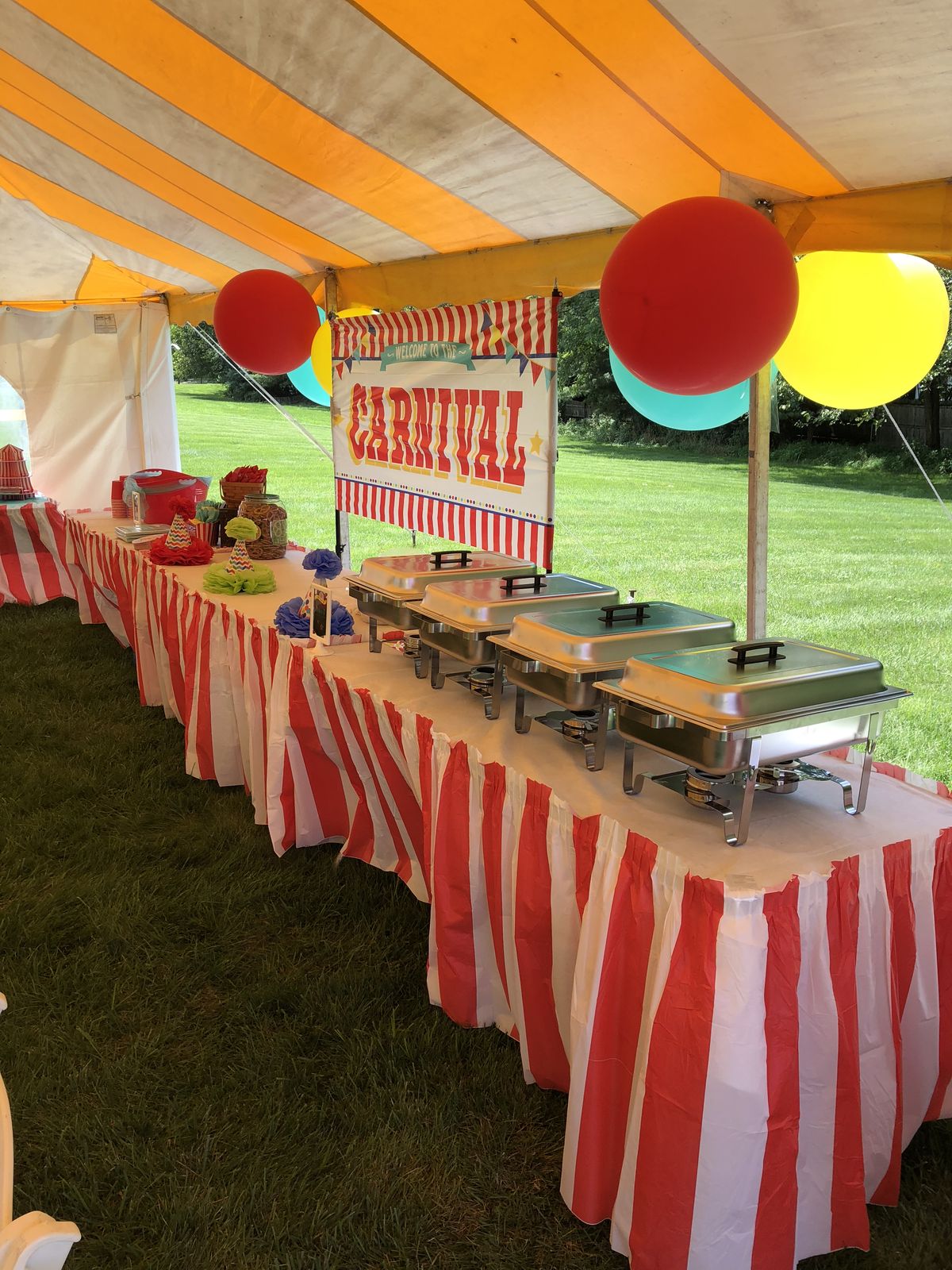 Carnival-style concession catering setup with chafing dishes, candy jars, and colorful decor